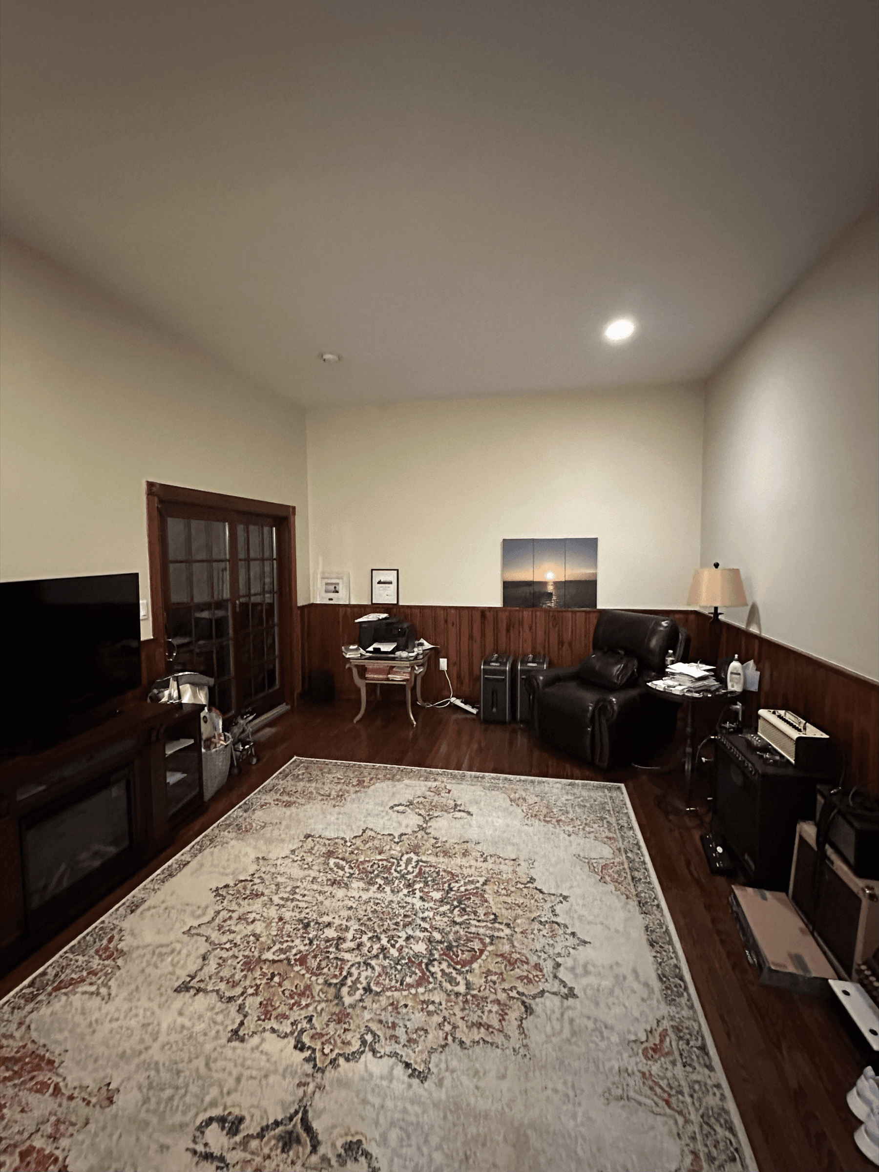 Family room with cream walls above wood wainscoting, before painting
